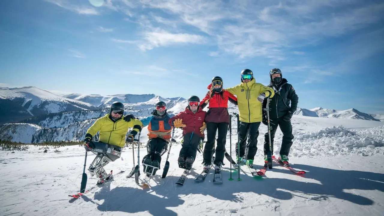 Skiers posing for a photo at the top of the mountain.