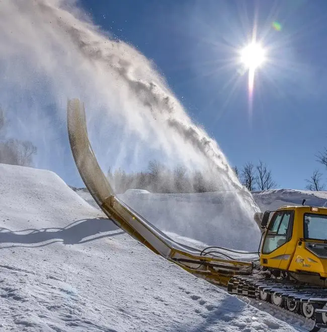 Snow cat spraying snow on a halfpipe feature