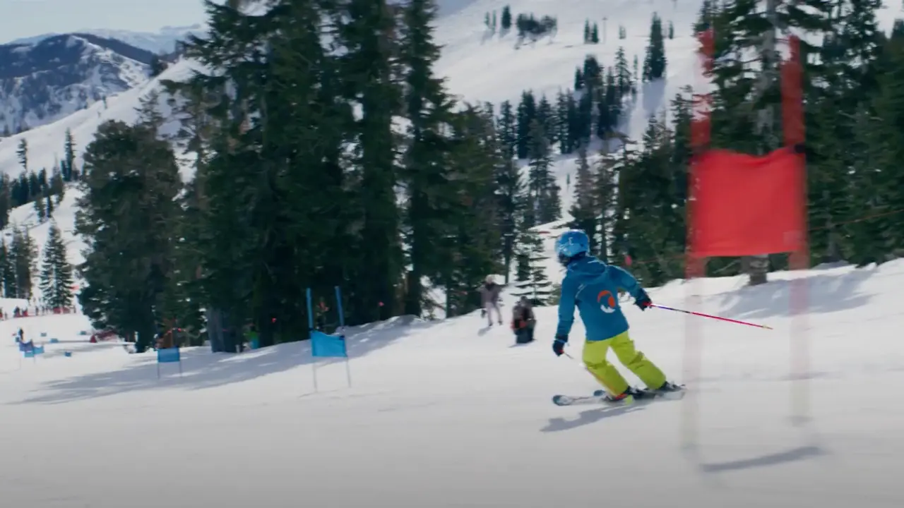 A young skier going through ski gates on a Nastar race course