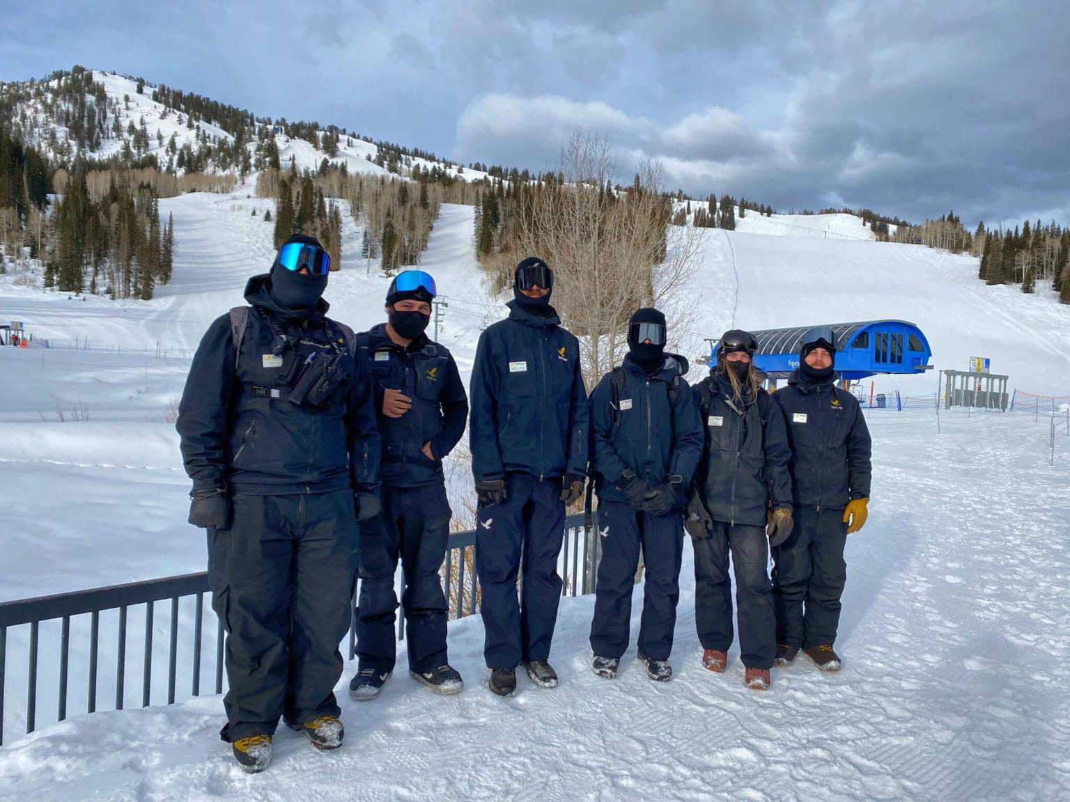 Group of people in winter/ski gear standing at the base of a ski resort in winter