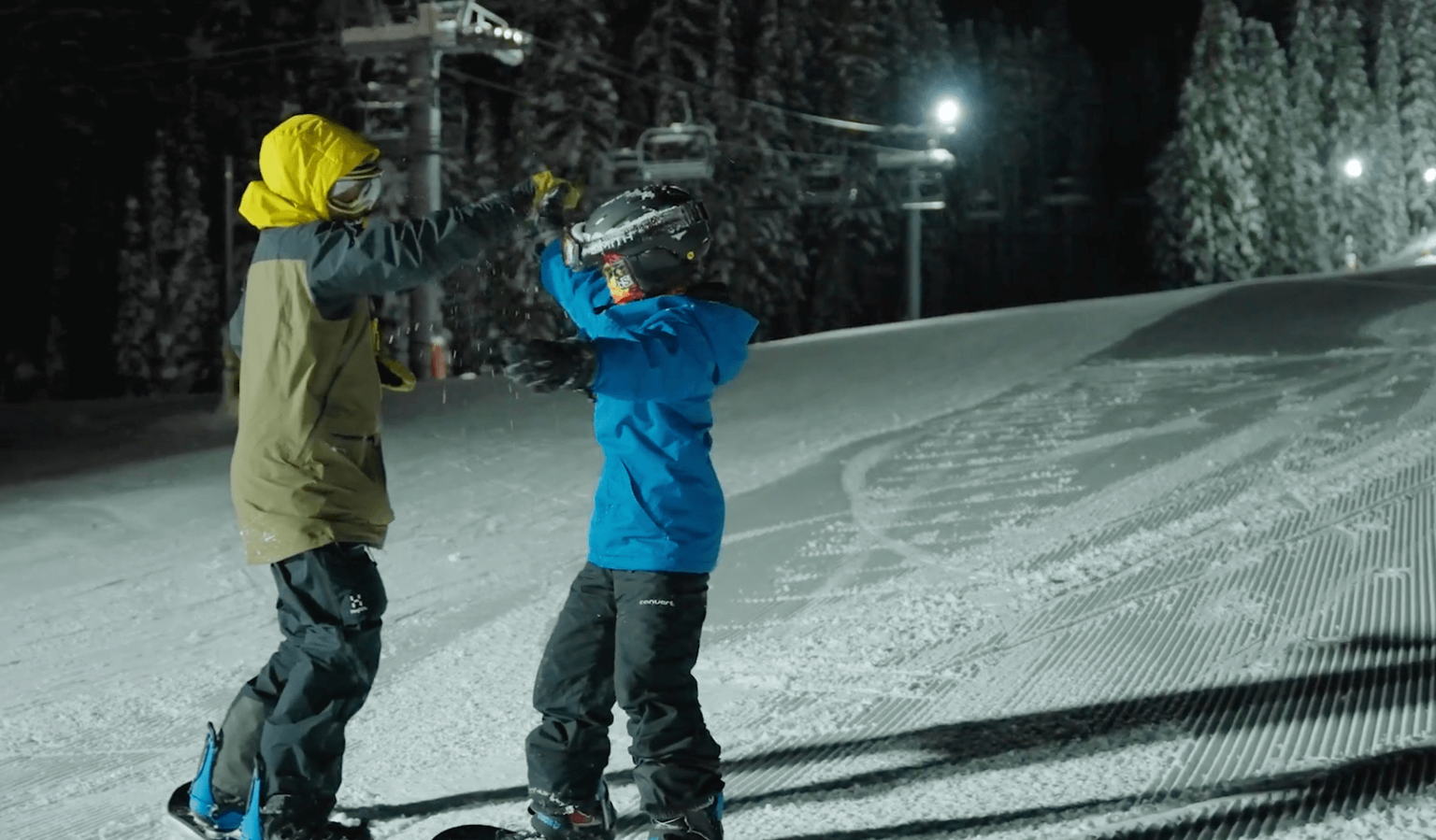 two people in snowboard gear giving each other a high five